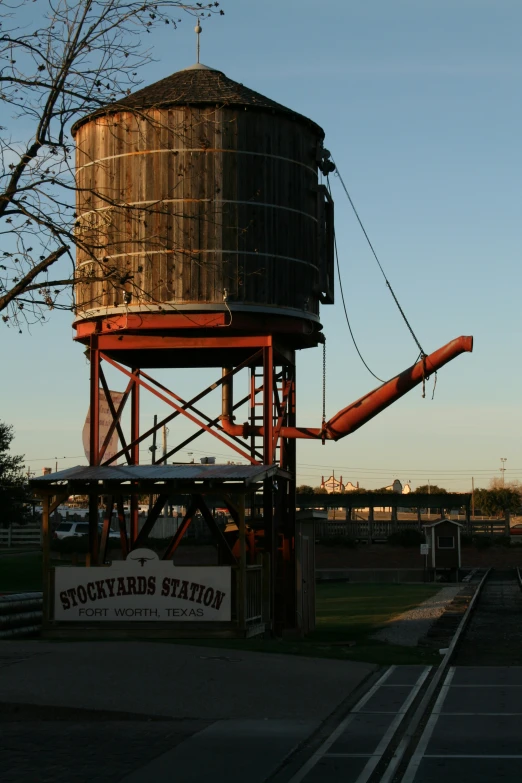 a brown water tower sitting next to train tracks