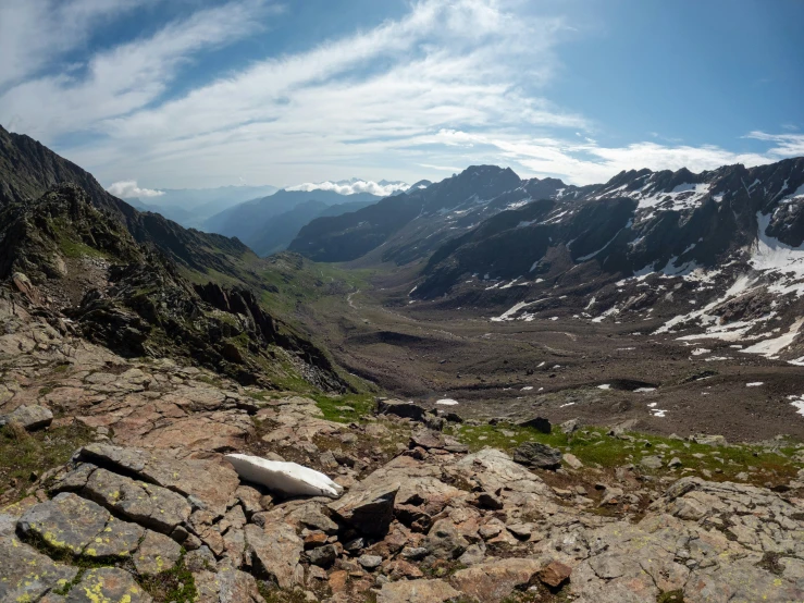 rocks with mountain peaks in the background, the sky is a blue with clouds