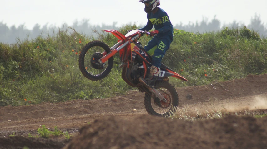 a person riding on the back of a motorcycle over a dirt track