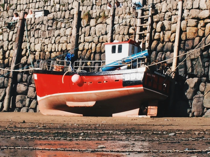 an old boat sitting on the beach by some rocks