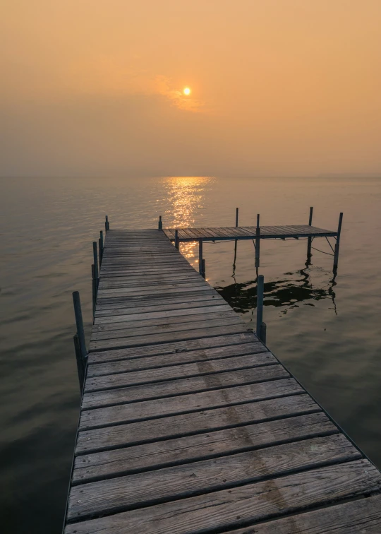 a dock with the sun in the distance