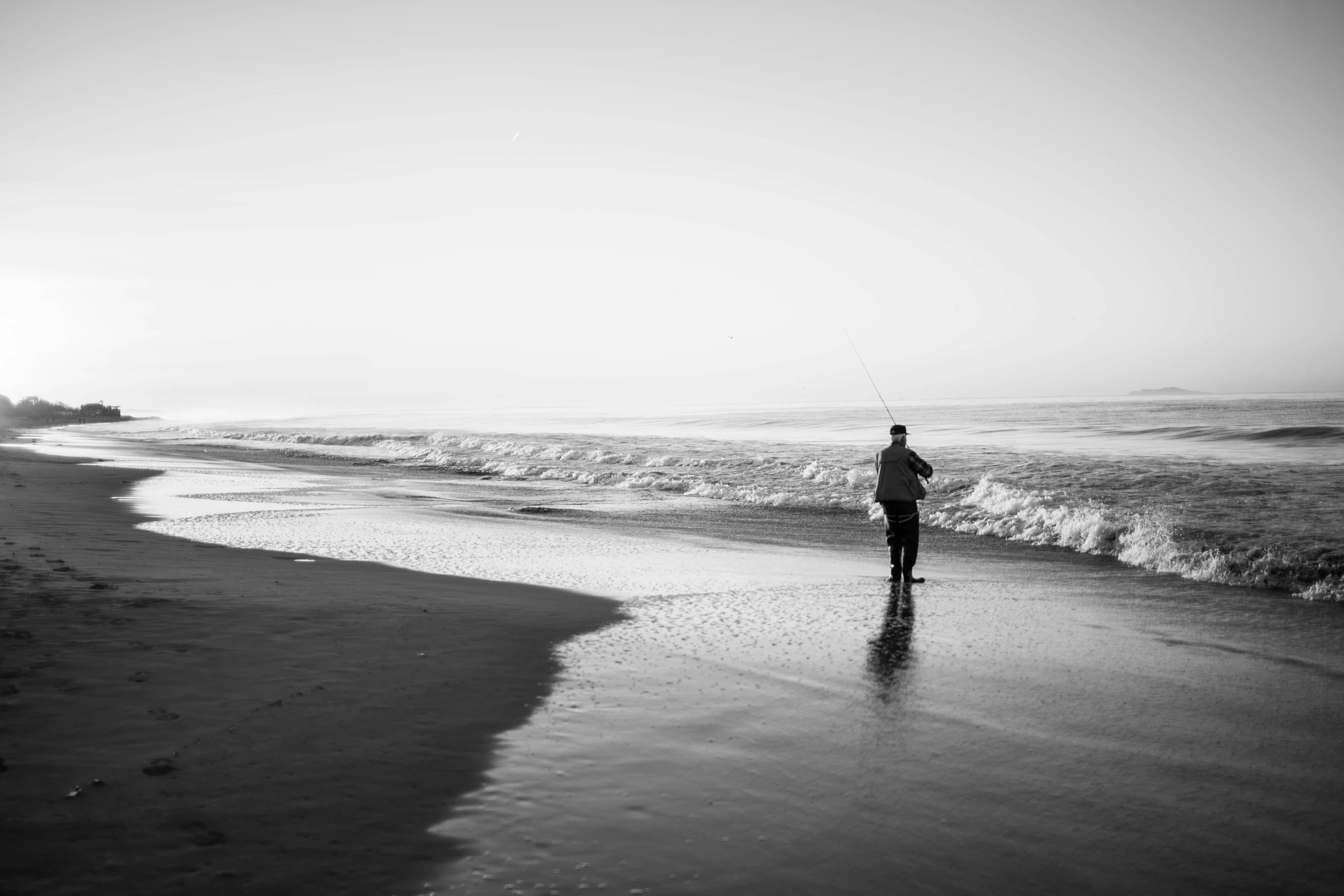 man wading along the beach holding a fish