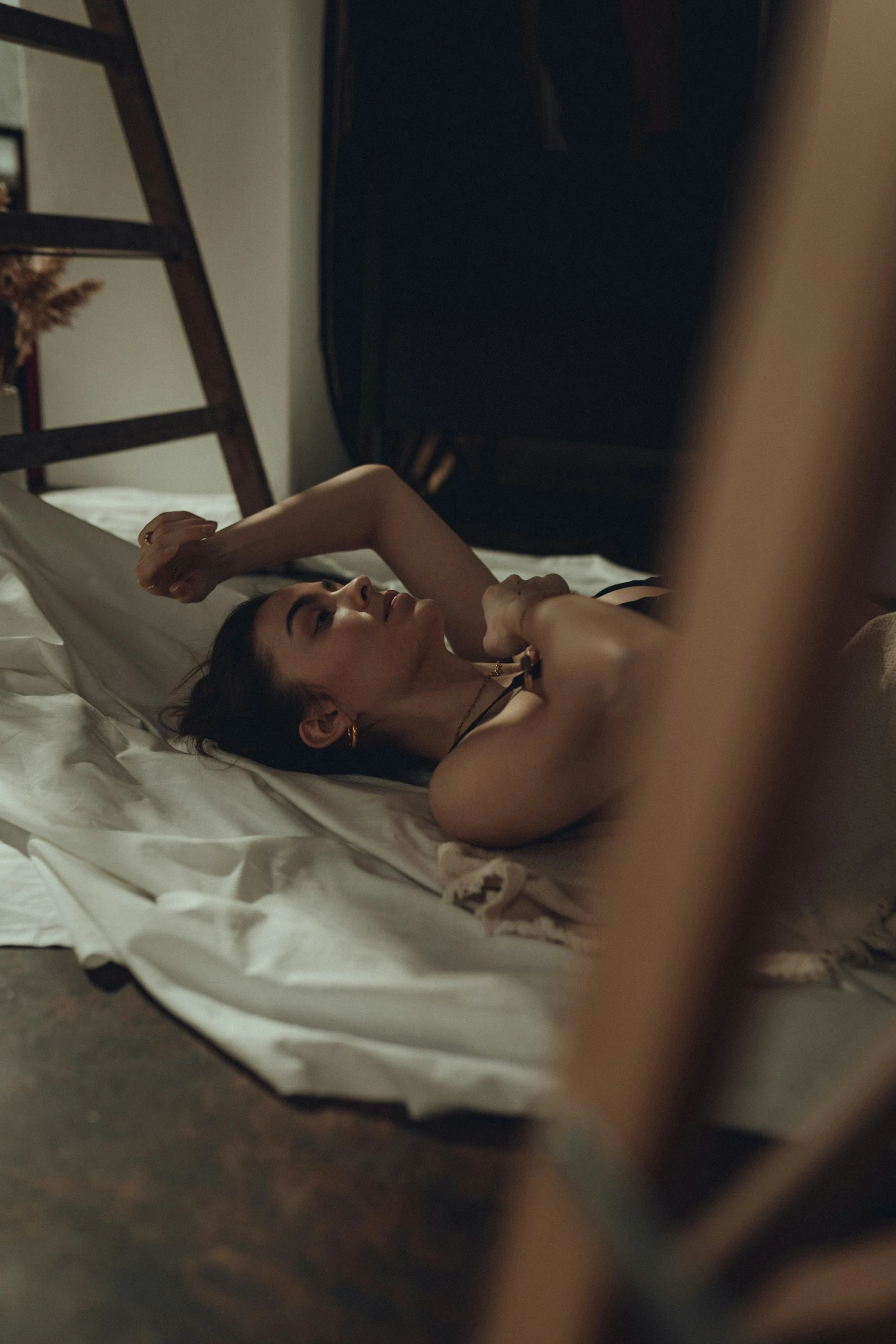 a woman laying on a bed underneath a wooden ladder