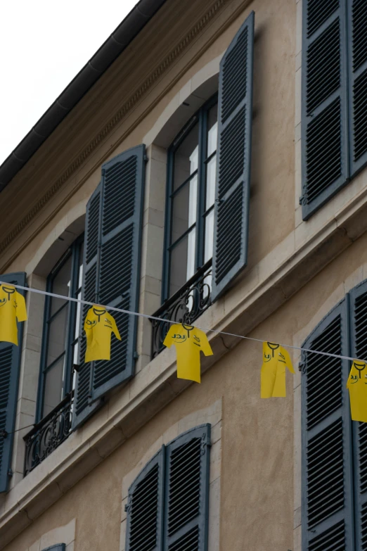 yellow shirts on clothes lines hanging from windows next to building