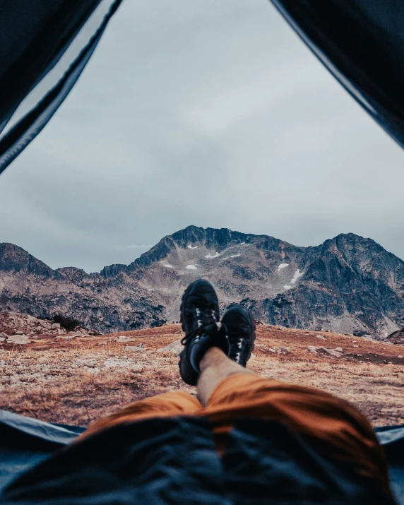 someone laying down in their camping tent with their legs up