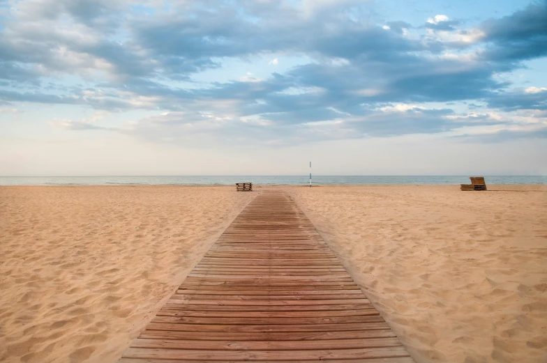 a boardwalk leading to the beach on a cloudy day