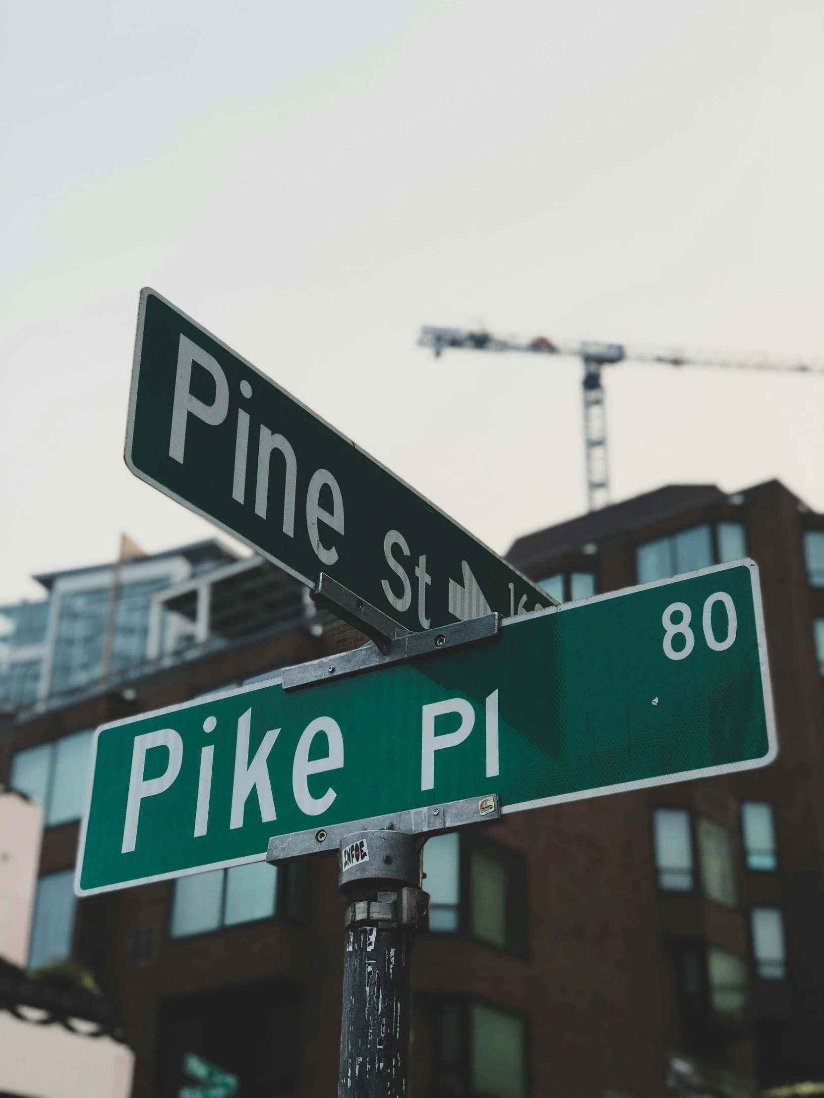 two street signs on top of a pole in front of a tall building