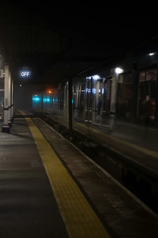 a train stopped at a lighted train station at night