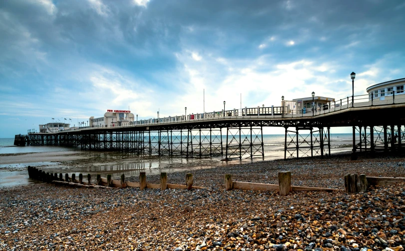 a very long pier on the beach with a long boat in the water