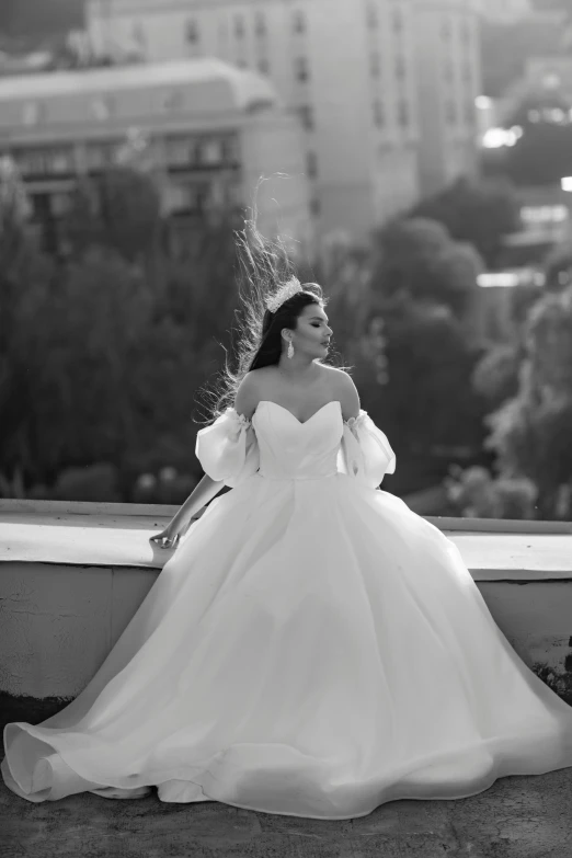 a woman in a ball gown looks down while standing on the ledge