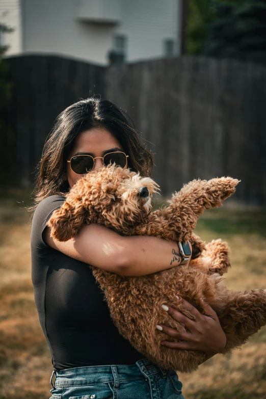 the girl in sunglasses is holding a brown dog