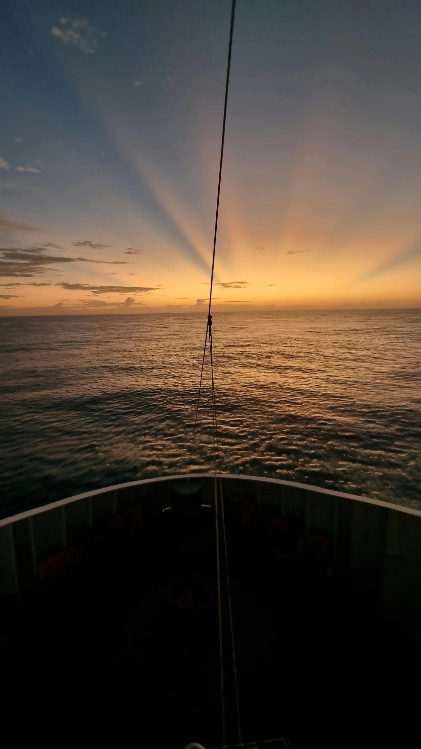 a sail boat floats on the ocean as the sun is setting