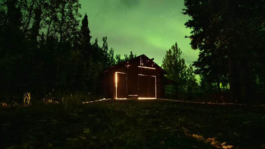 a barn with lights at night surrounded by trees