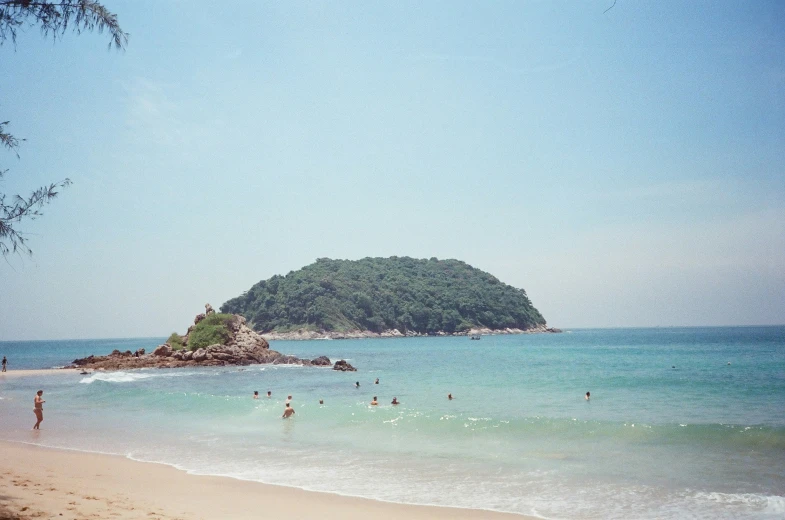 people standing in the water at a beach on an island