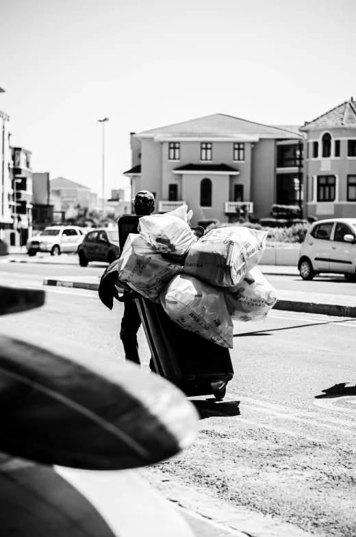 a man carrying huge bags of garbage across a street