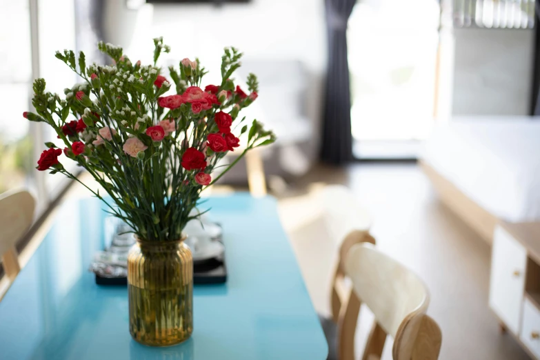 a blue table with a glass vase filled with flowers