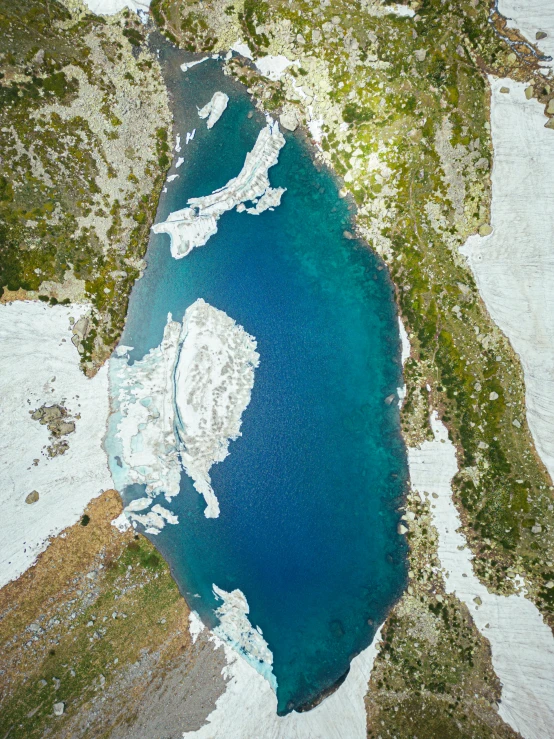 a blue lake is surrounded by snow and pine trees