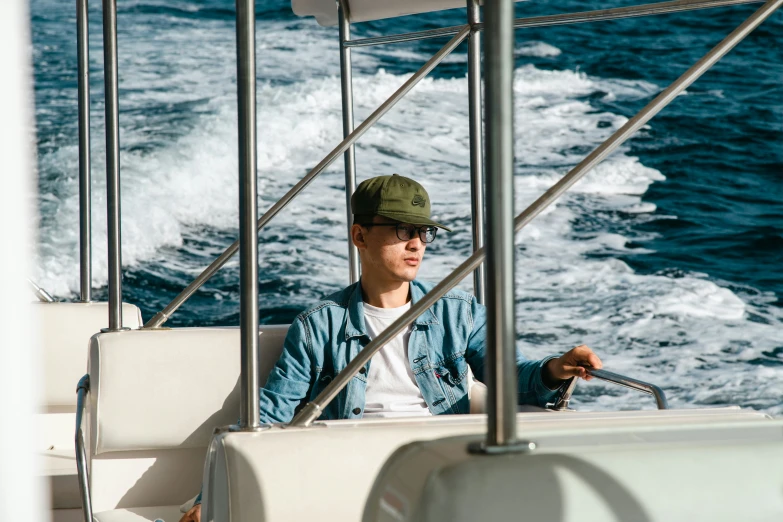 man sitting in the front of a boat looking at soing while holding his hand out