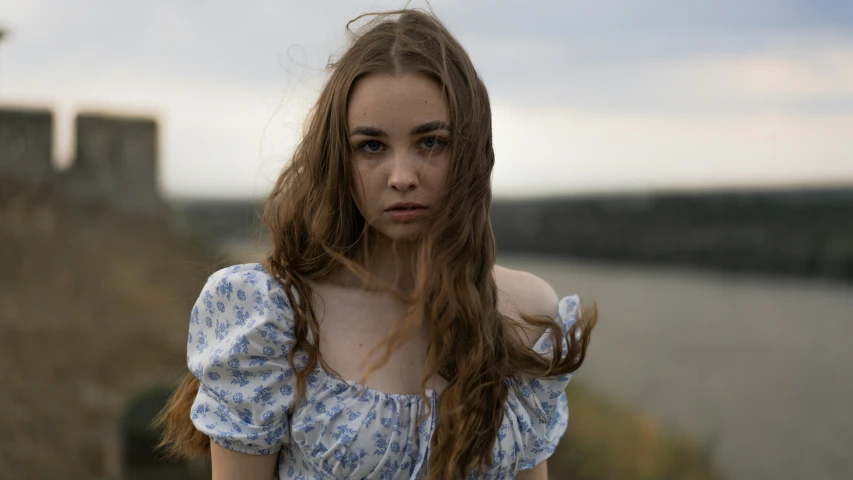 a girl with long red hair and a blue floral dress