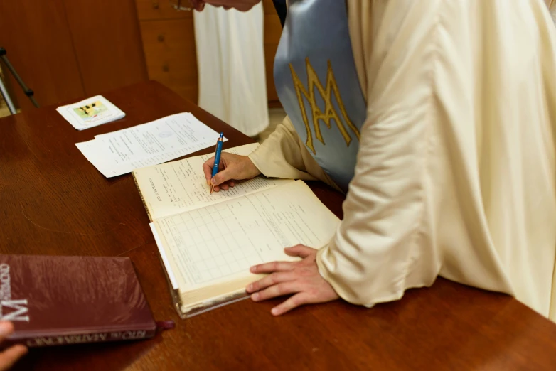 the person in the robe is signing into a notebook