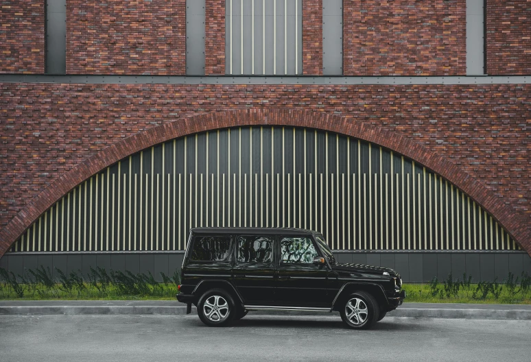 a black jeep is parked by a brick building