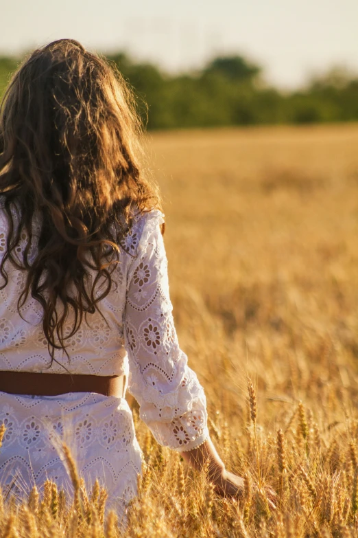 a little girl walks through a wheat field