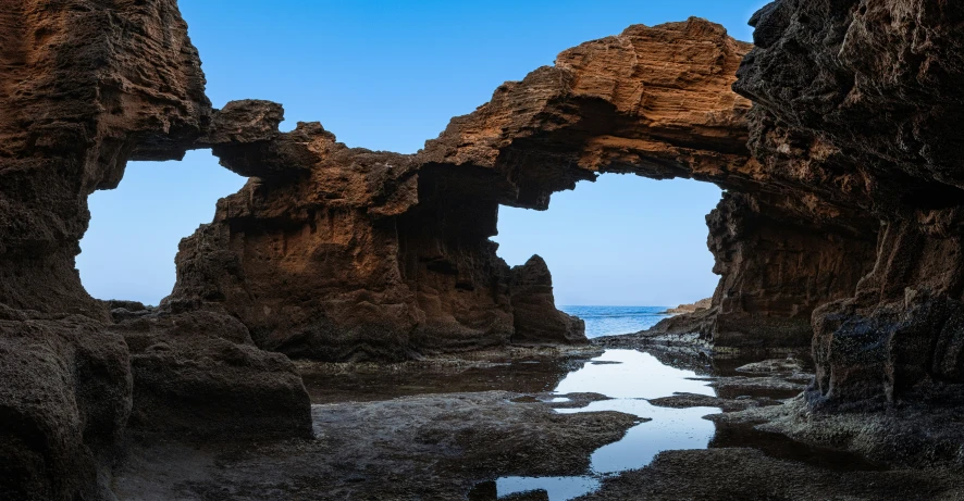 a rock cave with a water feature on a beach