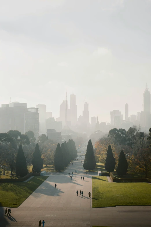 people walking through an open park with skyscrs in the distance