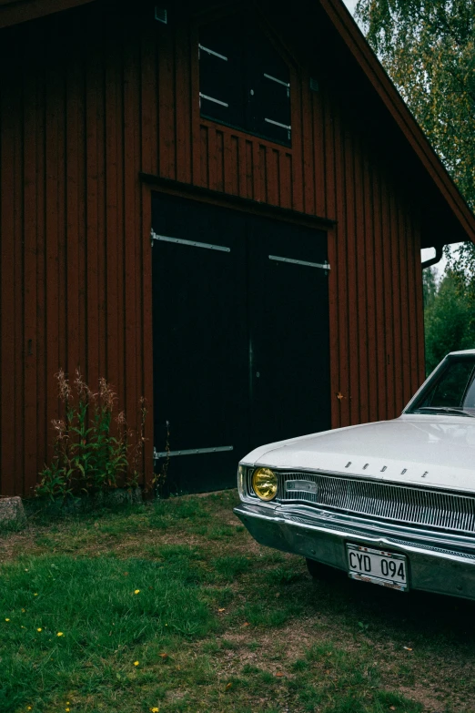 an old car parked in front of a barn