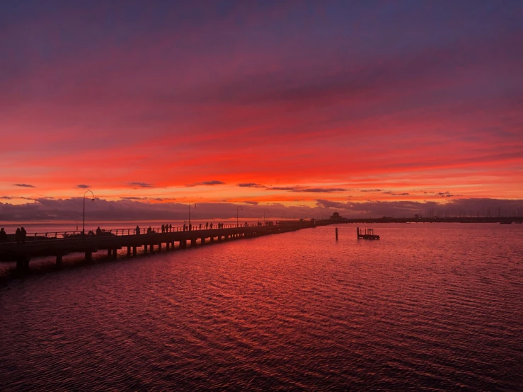 a large body of water under a red and purple sky