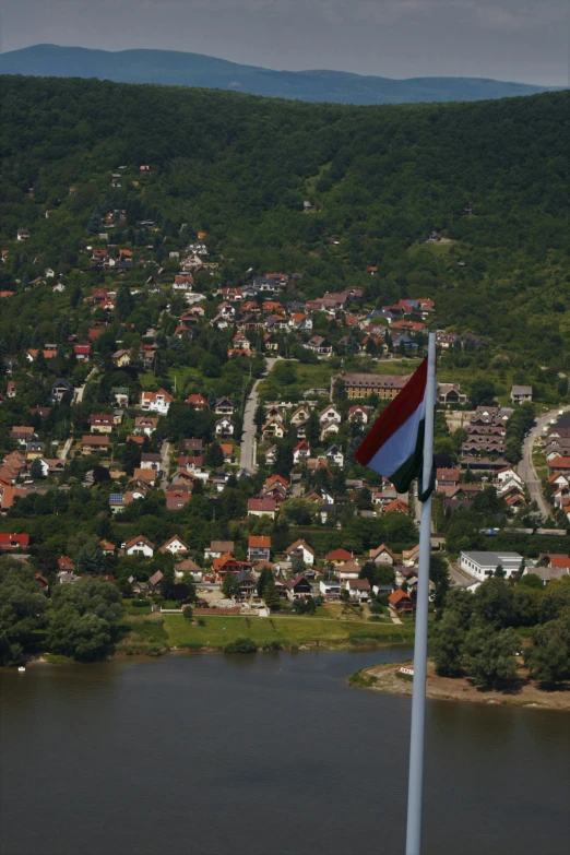 a flag is flying high on a mountain overlooking a small town