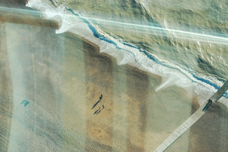 people on the beach next to the water from an aerial view