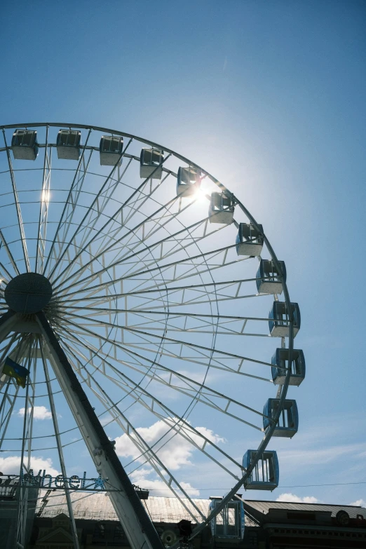 a big ferris wheel with the sun shining behind it