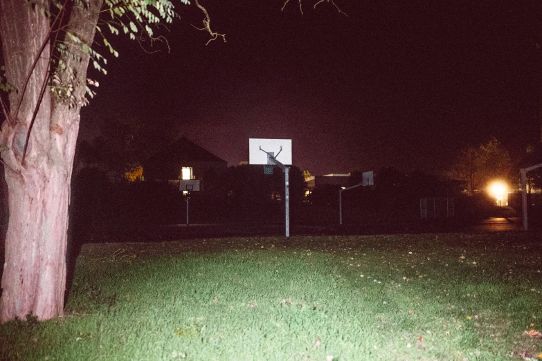 a view of a back yard at night, with a basketball hoop