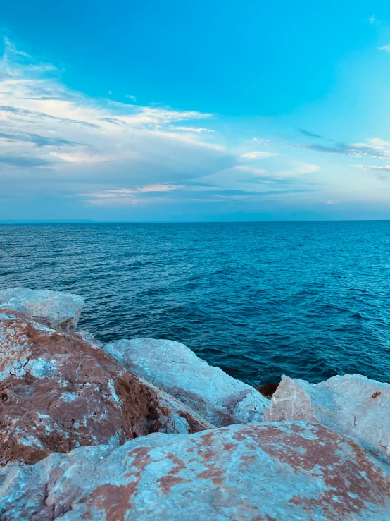 a boat traveling on the ocean near a rocky shore