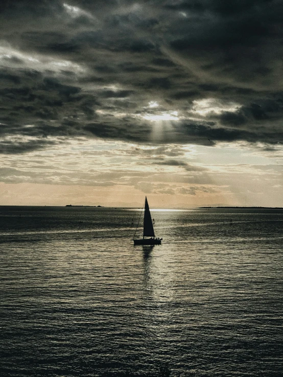 a sailboat sitting on the open ocean with an evening sky