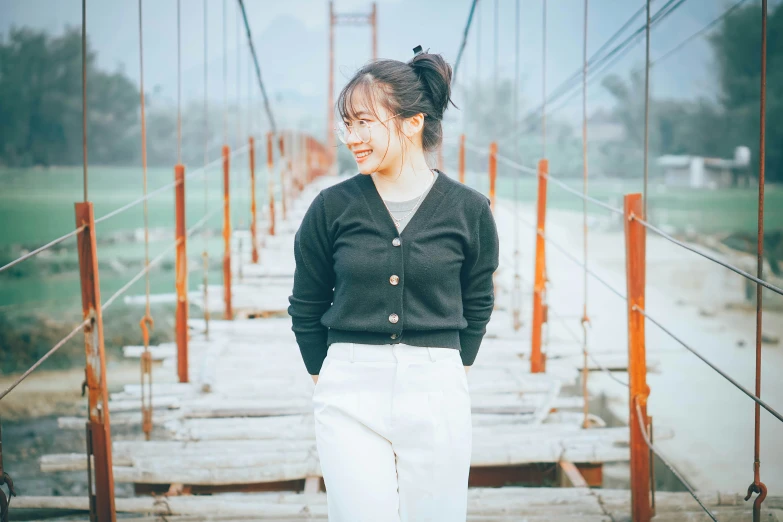 a woman standing on top of a wooden bridge