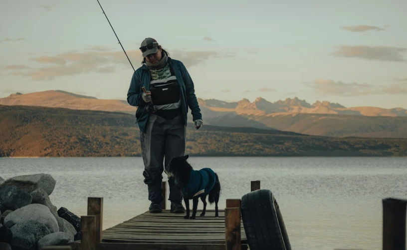 a man standing on top of a pier next to a dog