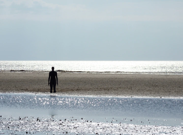 a person standing on the beach holding onto a surfboard