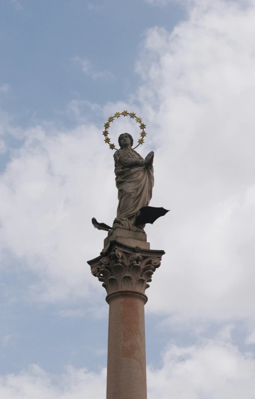 a statue of a standing angel on a pillar with a wreath