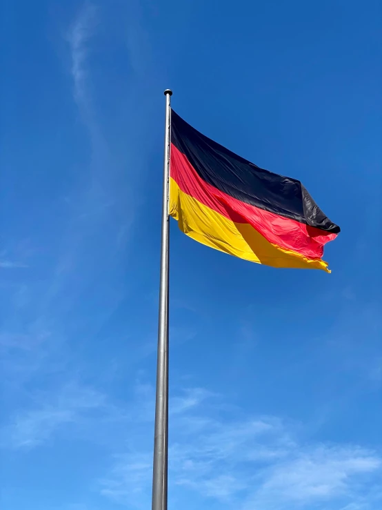 a flag blowing in the wind under a blue sky