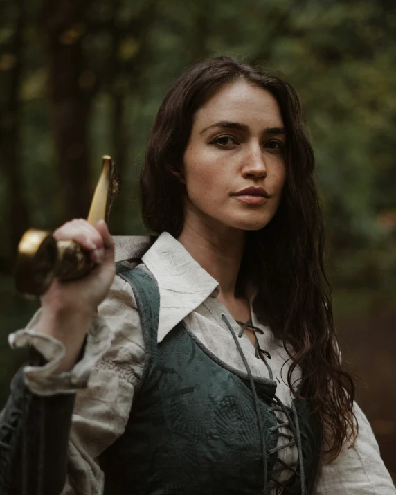 a woman is dressed in period clothing and has a knife in her hand