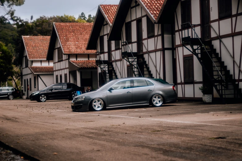 two cars parked near a building with stairs and a roof