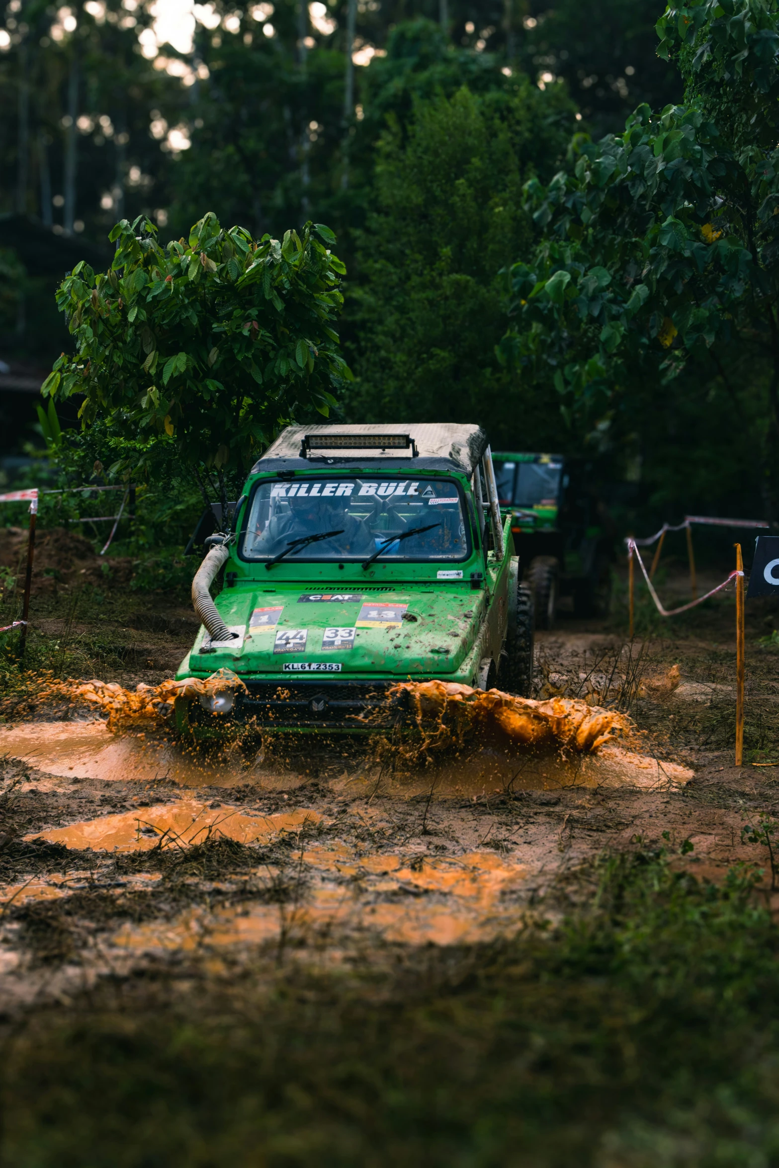 a green car driving in muddy roads and trees