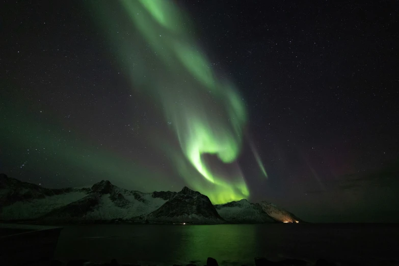 two aurora lights glow over some mountains and a body of water