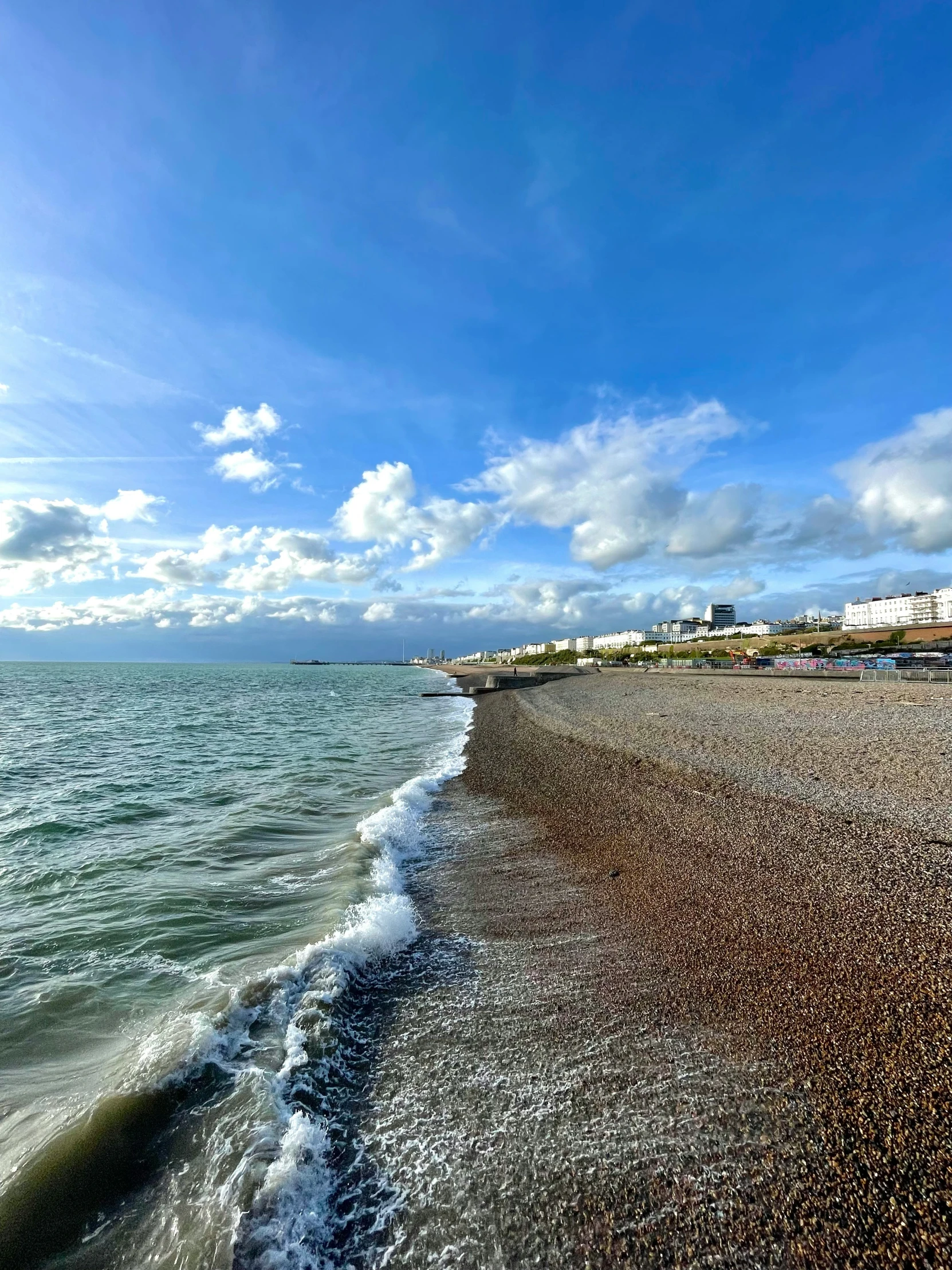 the waves roll into the beach with a city in the distance