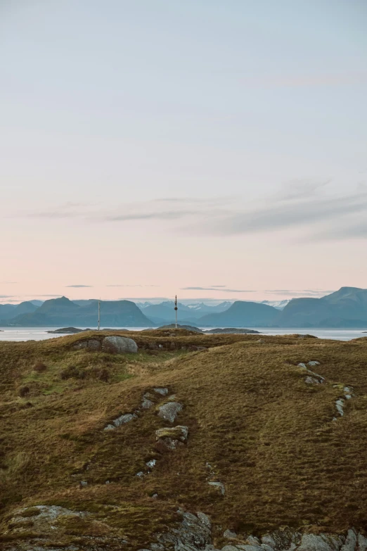 an area with grass and rocks near some mountains