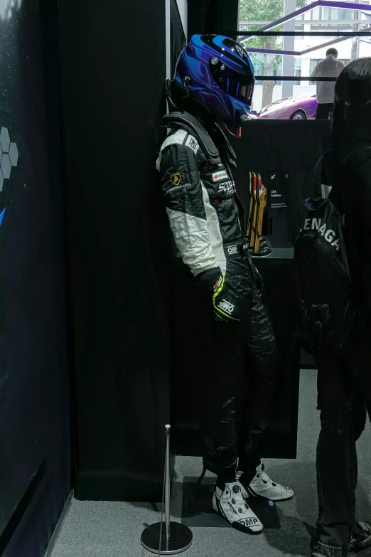 two people in racing gear stand inside an elevator