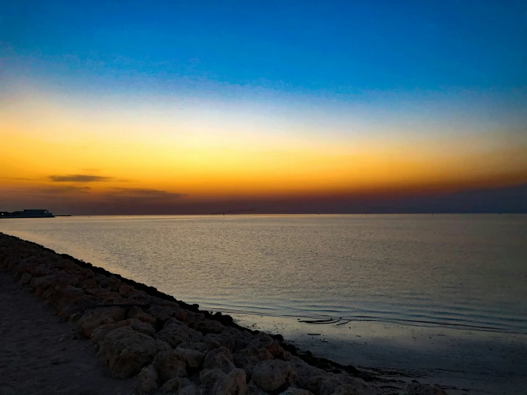 a man sitting on the beach watching the sunset