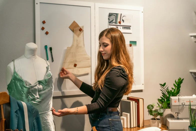 a lady is looking at her dress on the mannequin